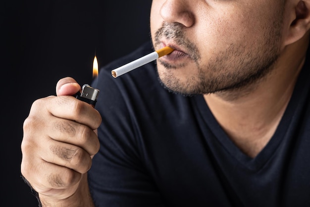 Foto um jovem com um cigarro ele vai fumar acendeu o isqueiro com um isqueiro, e a fumaça flutuou em volta.