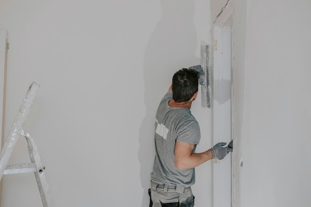 Um jovem construtor está rebocando uma porta