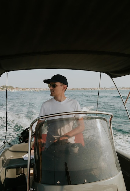 Um jovem controla um barco no mar