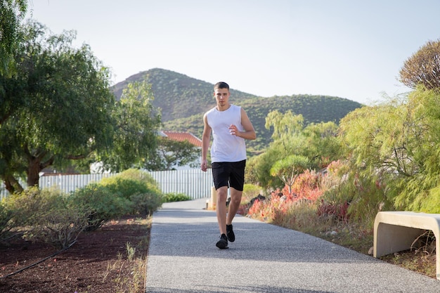 Um jovem corredor corre em um parque público, esportes e conceito de bem-estar
