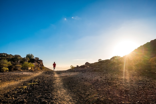 Um jovem correndo sozinho na montanha ao pôr do sol para se exercitar e ter um estilo de vida saudável fazendo jogging