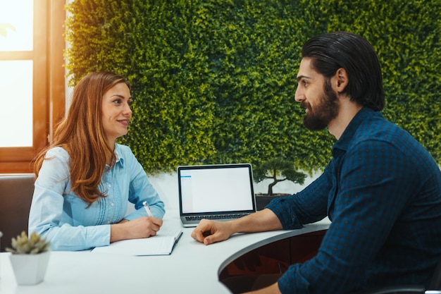 Um jovem dá uma entrevista para um emprego, e os dados são coletados por uma jovem.