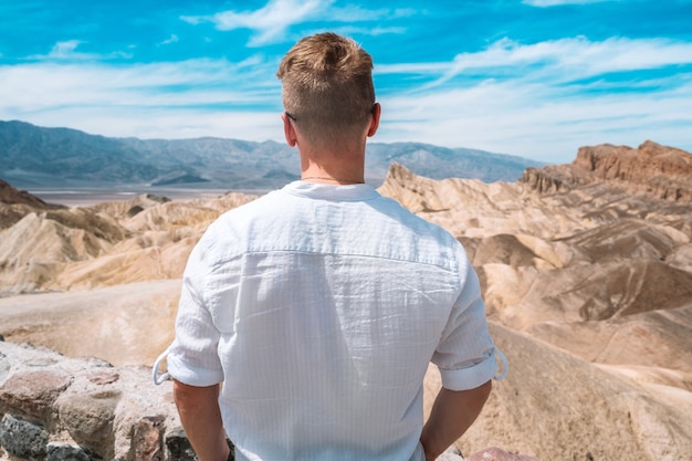 Um jovem de camisa branca caminha pelo pitoresco deserto do Vale da Morte