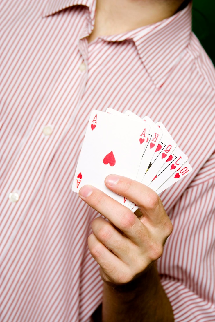 Foto um jovem de camisa listrada vermelha segurando royal flush