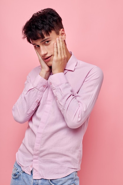 Um jovem de camisa rosa gesticulando com as mãos fundo rosa inalterado