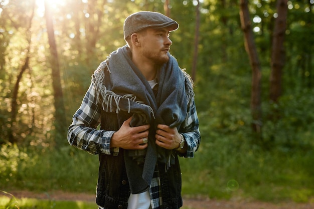 Um jovem de camisa xadrez com xadrez caminha em um parque ensolarado na floresta