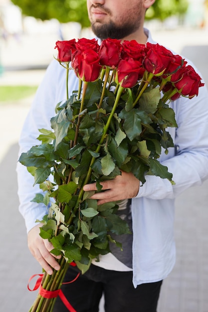 Um jovem de camisa xadrez e óculos com um grande buquê de rosas