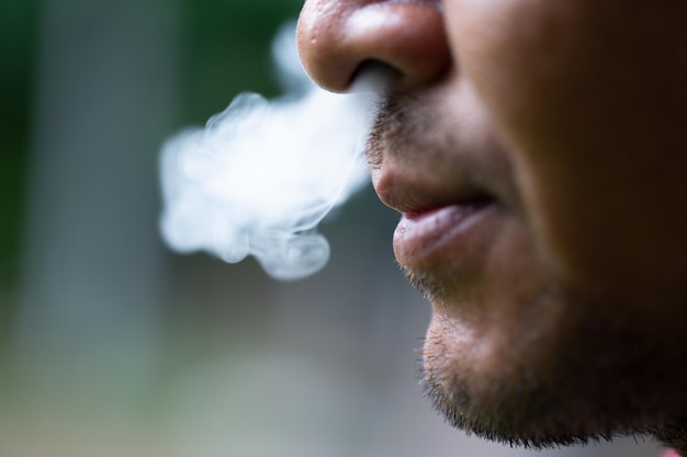 Um jovem de pé fumando um cigarro Conceito e ideias para parar de fumarfechar