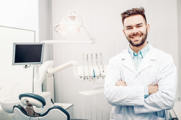 Um jovem dentista cheerfull masculino no consultório do dentista