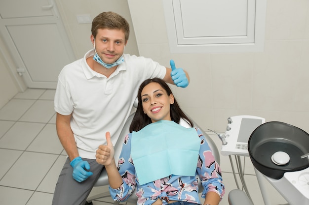 Um jovem dentista masculino e feliz paciente do sexo feminino, cena de estilo de vida de escritório de dentista, prática médica, cuidados de saúde do paciente