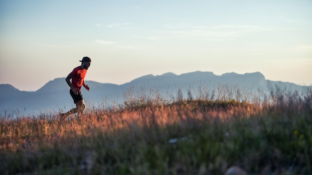 Um jovem desportista corre ao pôr do sol nas colinas