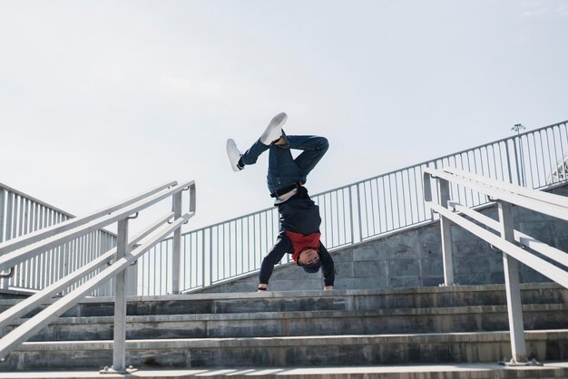 Um jovem do sexo masculino em movimento acrobático livre na rua da cidade, belo exercício físico