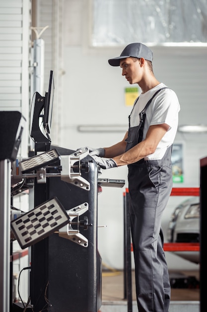 Um jovem e qualificado mecânico está trabalhando nos detalhes de uma oficina de automóveis.