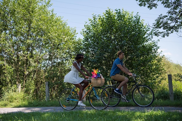 um jovem e uma linda garota afro-americana desfrutando de um passeio de bicicleta na natureza em um dia ensolarado de verão