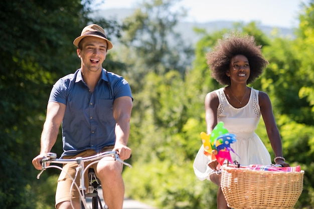 um jovem e uma linda garota afro-americana desfrutando de um passeio de bicicleta na natureza em um dia ensolarado de verão