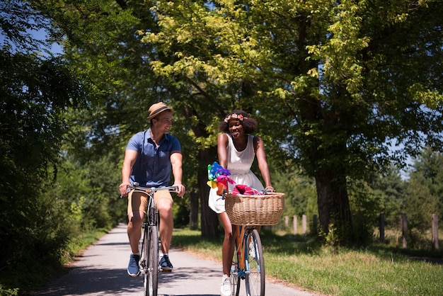 um jovem e uma linda garota afro-americana desfrutando de um passeio de bicicleta na natureza em um dia ensolarado de verão