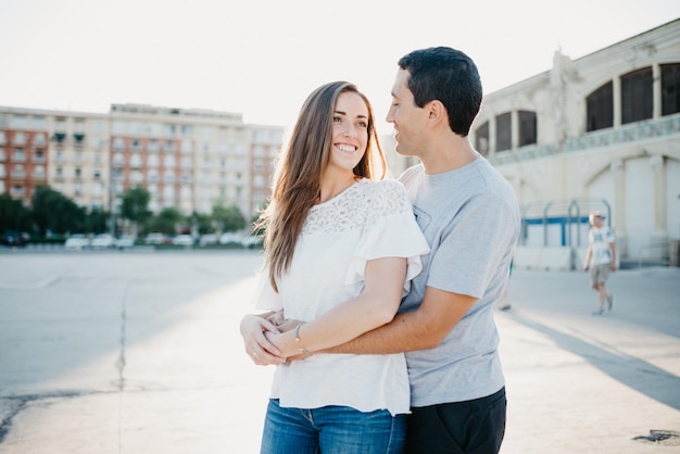 Um jovem elegante está de mãos dadas com sua namorada morena no porto