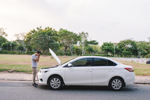 Um jovem em desespero agarrou sua cabeça, porque seu carro quebrou na estrada e não é possível consertá-lo.