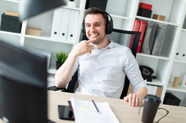 Um jovem em fones de ouvido se senta em uma mesa de computador.