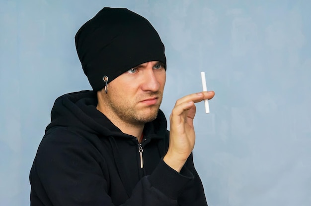 Um jovem em roupas de juventude da subcultura segurando um cigarro