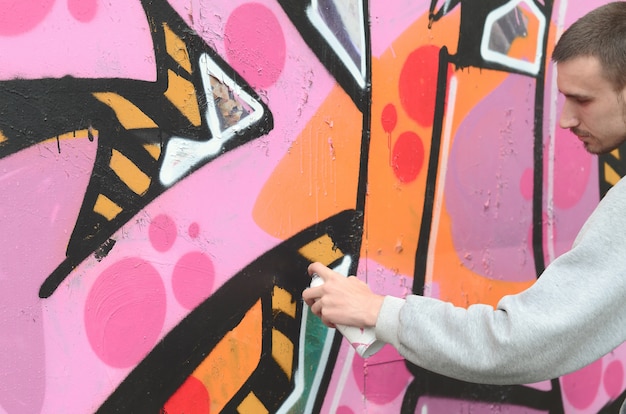 Um jovem em um capuz cinza pinta graffiti