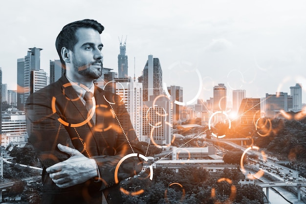Um jovem empresário caucasiano em pose de braços cruzados ponderando sobre a tecnologia no processo de negócios para alcançar um tremendo crescimento Ícones de holograma de tecnologia sobre fundo de Kuala Lumpur