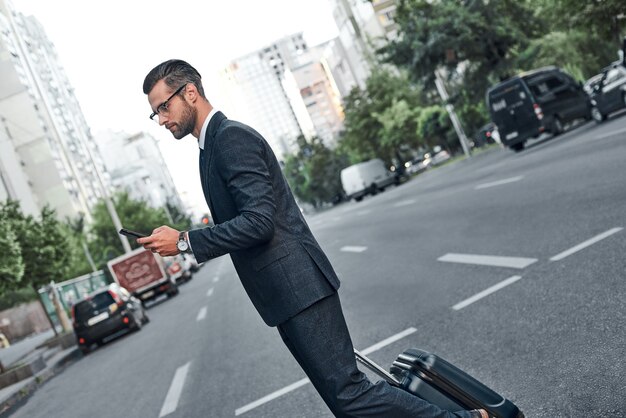 Um jovem empresário com óculos está conversando em seu smartphone e atravessa a rua