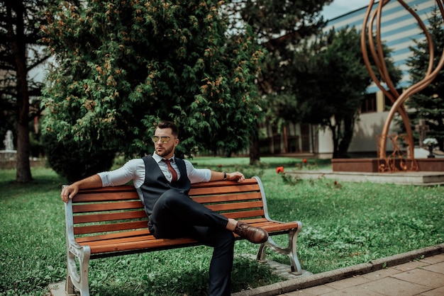 Um jovem empresário sexy de terno sentado no parque na pausa do trabalho