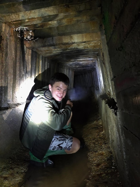 Um jovem escavador sentou-se no túnel do coletor de esgoto em perspectiva