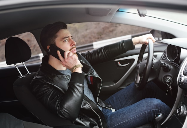 Um jovem está falando ao telefone enquanto dirige um carro.