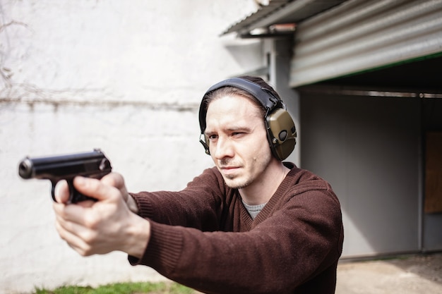 Foto um jovem está mirando em uma arma. um homem usando fones de ouvido protetores.