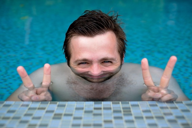 Um jovem está tomando banho na piscina e descansando durante as férias Seu rosto está distorcido por causa da água