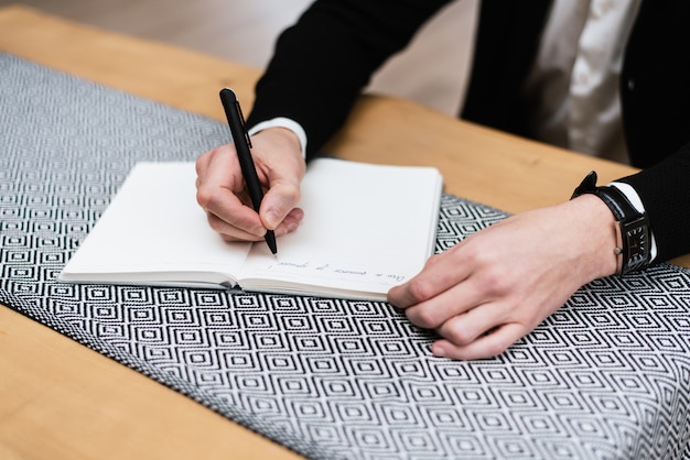 Um jovem está trabalhando em seu escritório. o professor se prepara para a palestra. designer mão trabalhando no notebook na mesa de madeira no escritório