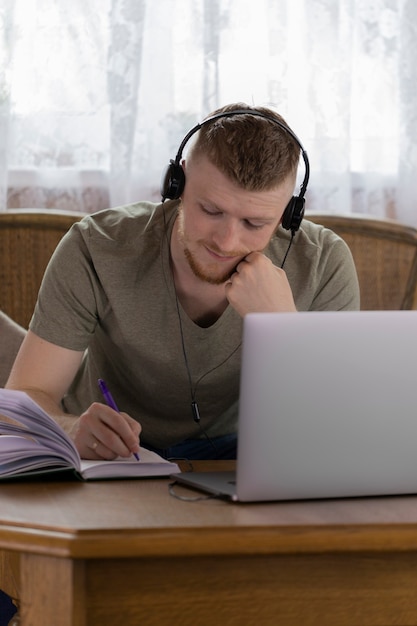 Um jovem estudante está estudando na universidade remotamente de casa usando um laptop