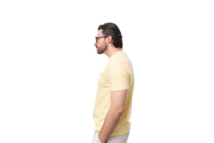 Foto um jovem europeu elegante, esperto, com caule e bigode, vestido com uma camiseta amarela clara.
