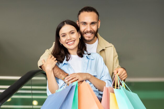 Um jovem europeu positivo com bolsas abraçando uma mulher aproveita a venda de compras e caminha no tempo livre