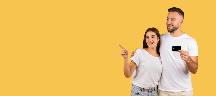 Foto um jovem europeu sorridente e uma senhora de camisa branca com cartão de crédito abraçam-se apontando o dedo.