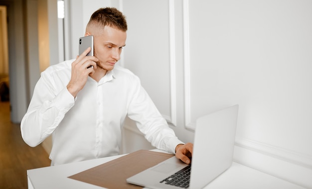 Um jovem fala ao telefone e verifica as informações sentado em casa na cozinha