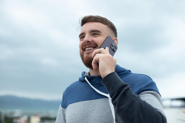 Um jovem feliz falando no celular na rua fazendo uma ligação se sentindo feliz e