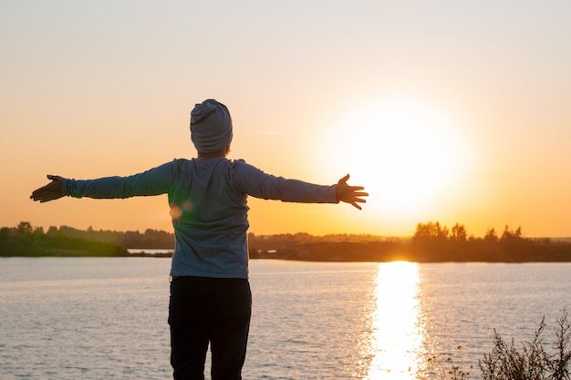 Um jovem fica em um lago ao pôr do sol