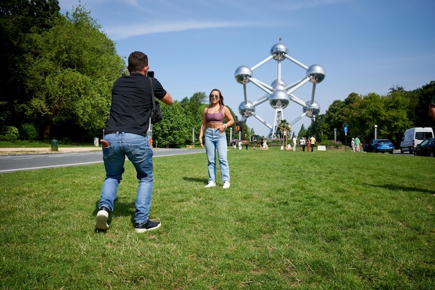 Um jovem hispânico tirando uma foto de sua namorada posando no atomium bruxelas bélgica