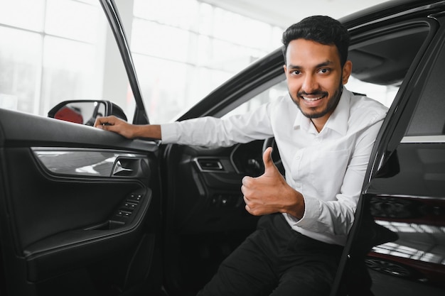 Um jovem indiano escolhe um carro novo em uma concessionária