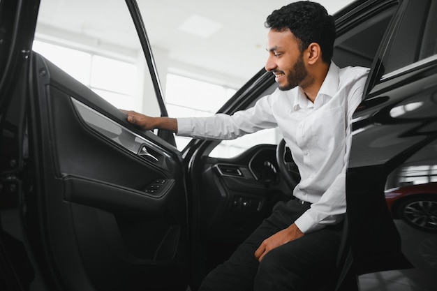 Um jovem indiano escolhe um carro novo em uma concessionária