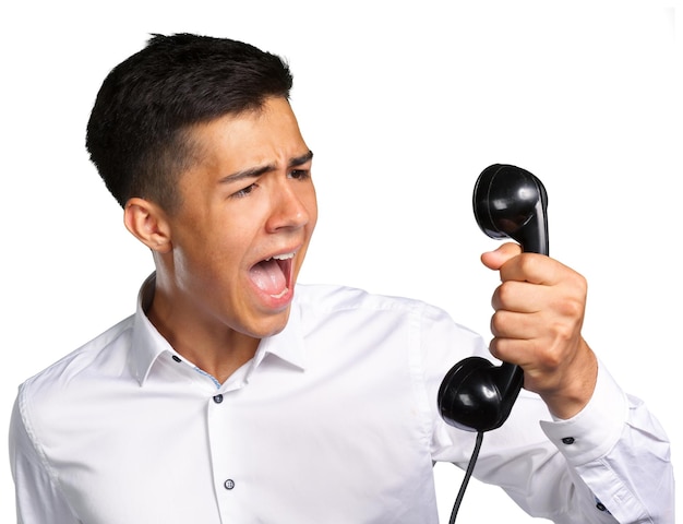 Um jovem irritado e irritado grita para o receptor de telefone