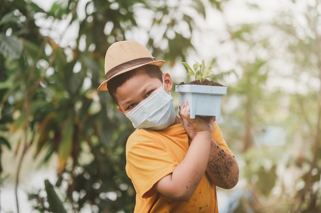 Um jovem jardineiro carrega um vaso de mudas de plantas para plantar no chão