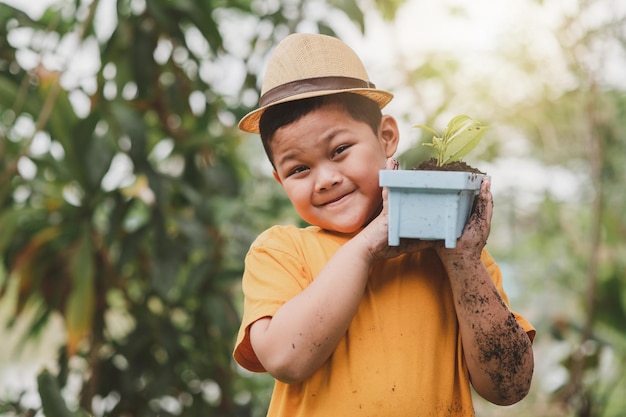 Um jovem jardineiro carrega um vaso de mudas de plantas para plantar no chão