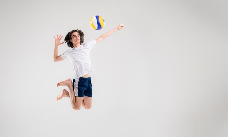 Foto um jovem jogador de vôlei está treinando com uma bola em um fundo branco conceito de aptidão da equipe de saúde do esporte de ação
