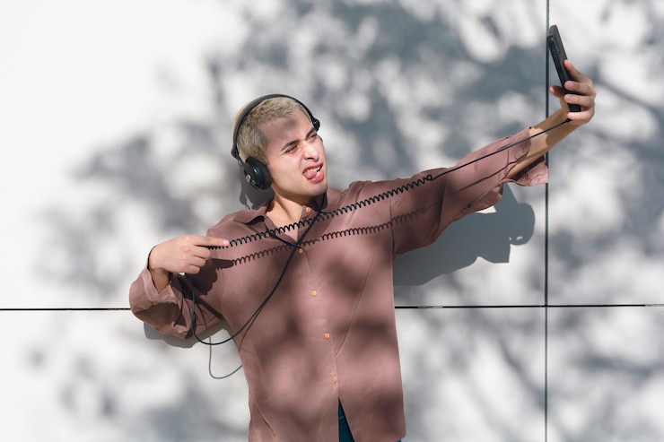 Foto um jovem latino com fones de ouvido e telefone celular está tirando uma foto selfie