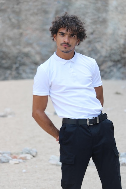 Um jovem latino na areia vestindo camisetas brancas