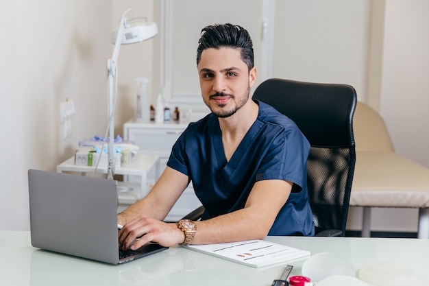 Um jovem médico árabe ou turco de uniforme azul dá aconselhamento online